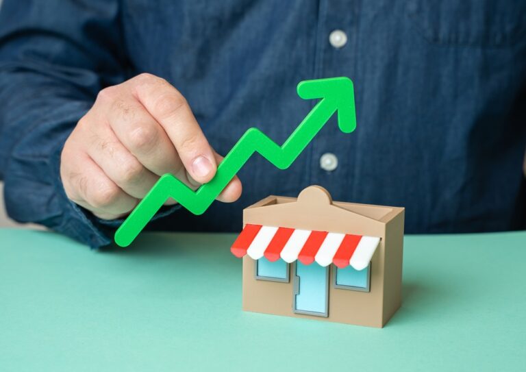 A man holds a green arrow pointing up over a store. Growing store profits, expanding and increasing coverage. Business is going well. Revenue growth. Market success. Expansion strategy. High sales.