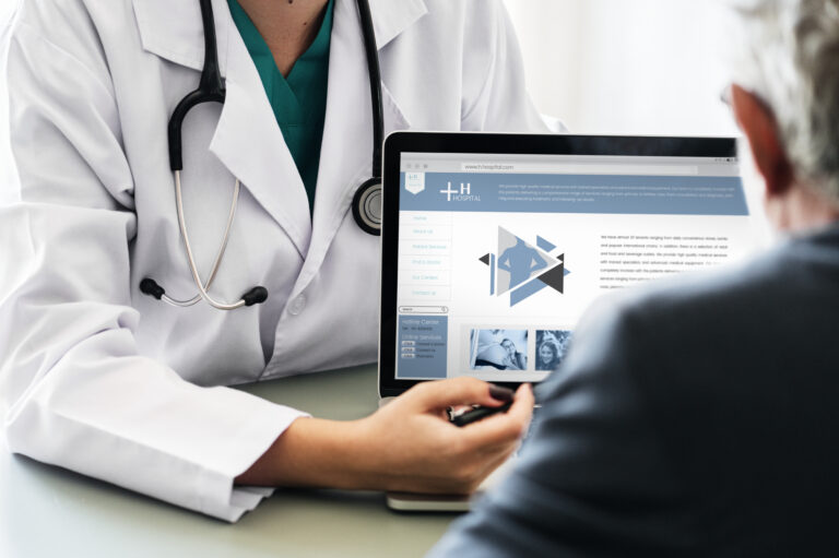 Doctor showing a patient a clinic website on a laptop during a medical website redesign review